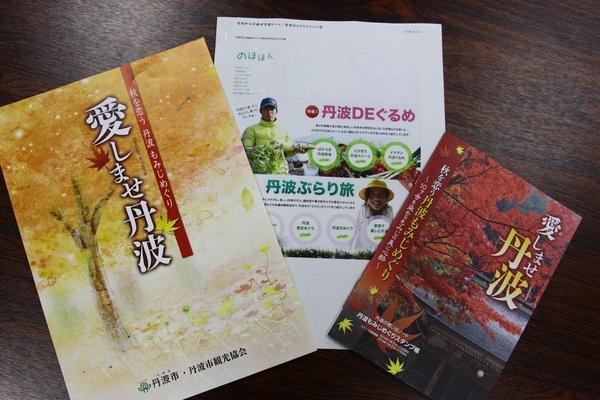 左から黄色いもみじが描かれ愛しませ丹波と書かれたパンフレット、真ん中に丹波DEぐるめ、丹波ぶらり旅が載っている白い紙、右側に赤いもみじが写り、愛しませ丹波と書かれているパンフレットの写真